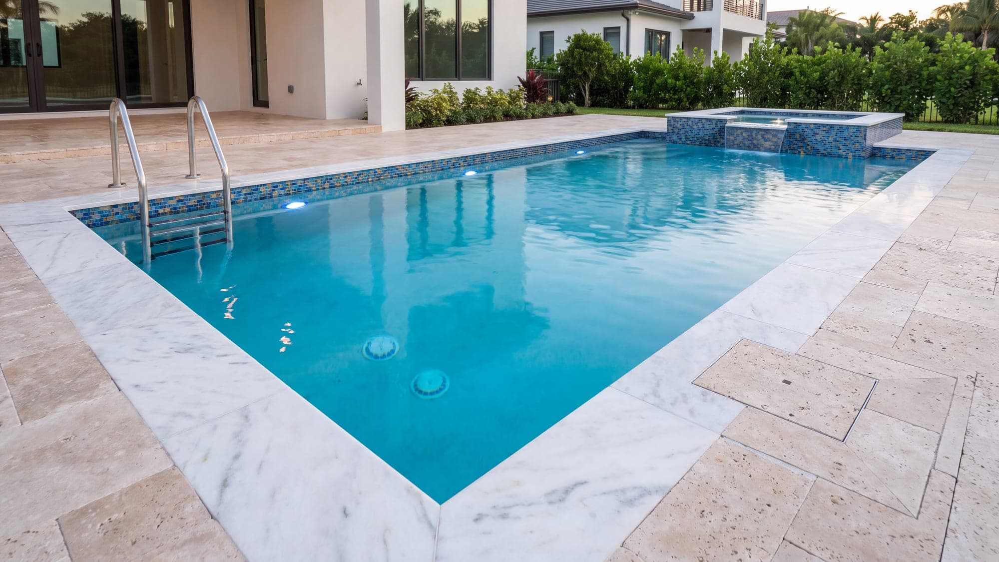 A finished pool showing coping, waterline tiling, lighting, ladder and skimmer.