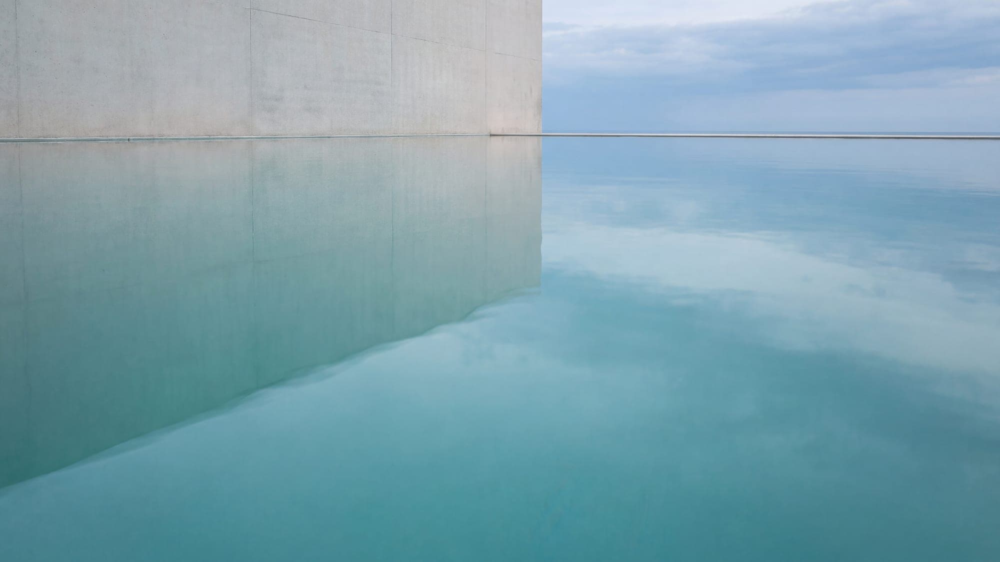 Still pool water holding a soft architectural reflection.